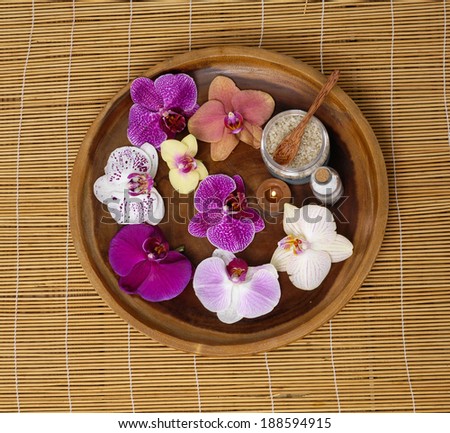 Wooden bowl of colorful orchid with spa sitting on mat