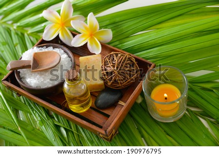 spa supplies with frangipani. Sat in bowl, oil, candle on palm background