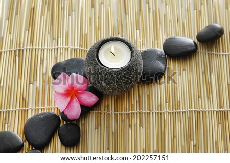Pink frangipani and row of stone with candle mat texture