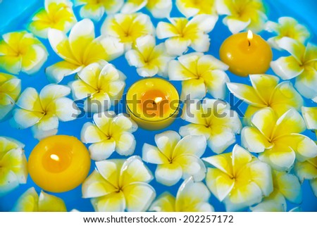 Many frangipani with three yellow candle in the water