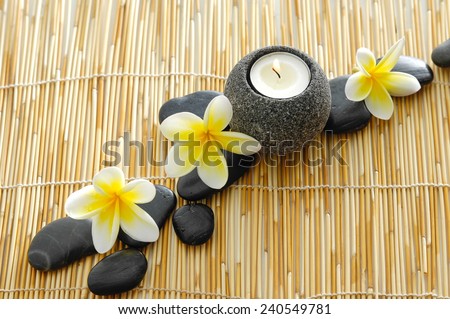beautiful frangipani and stones ,candle, and wooden mat