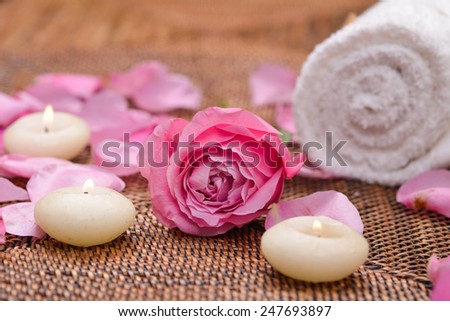 rose and petals with white candle on mat