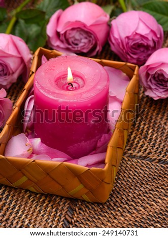 Spa set with pink rose and petals with pink candle in basket on mat