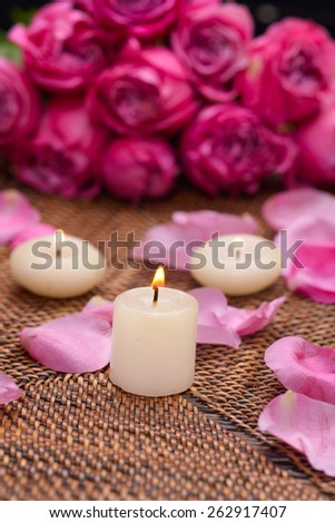 rose and petals with white candle on mat