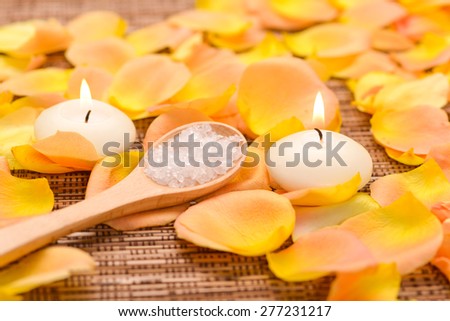 rose and petals with white candle, salt in spoon on mat