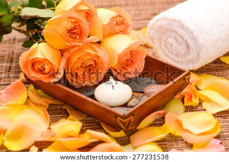 rose and petals with white candle in basket, towel on mat