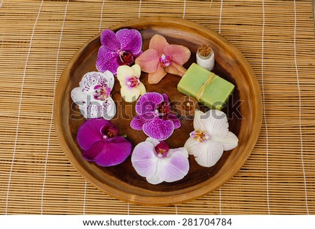 Wooden bowl of colorful orchid with soap,candle on mat
