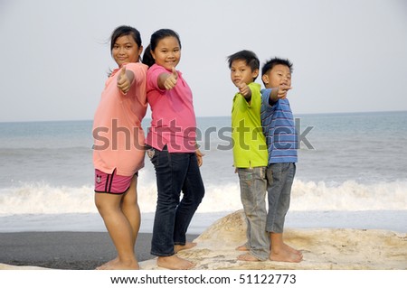 Asian little kids standing back to back  on the beach