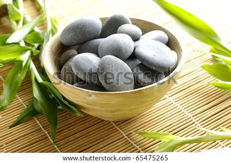 Bowl of stones with green plant on mat