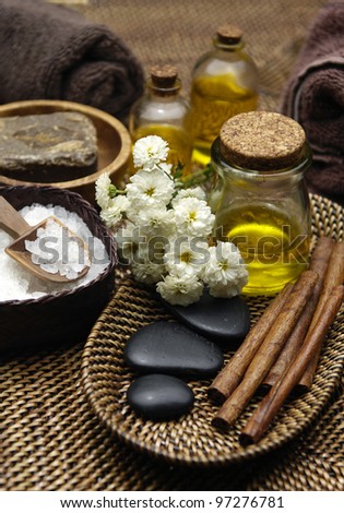 massage oil and stone in bowl and with gerbera on burlap texture