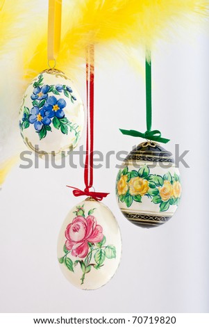 Easter table decorations, hand-painted eggs hanging on a vase with feathers