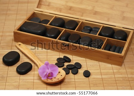 box with stones for massage and with flower of the orchid