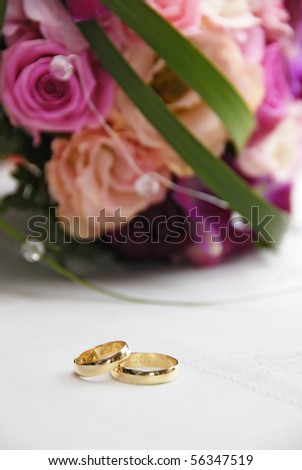 golden wedding rings on the table with flowers in the background