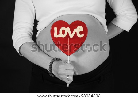 pregnant woman keeping the red lillipop with the love inscription