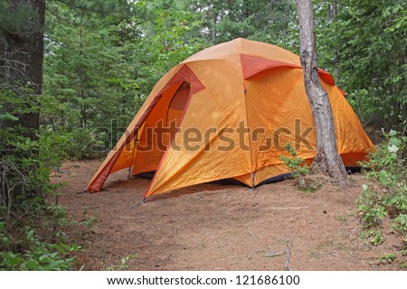 An orange tent sitting in Algonquin Provincial Park in Ontario, Canada.