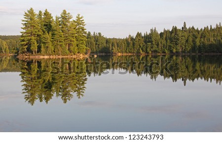 The reflection of the treeline and an island in Burnt Island Lake in Algonquin Provincial Park, Ontario, Canada.