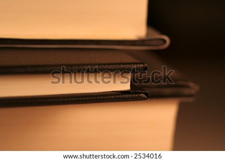 A side view of a little black book in between two bigger ones. (shallow depth of field)