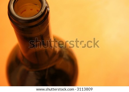 A red wine bottle rim set against a yellow background.