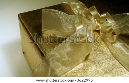A wedding gift wrapped in gold metallic paper and ribbons.