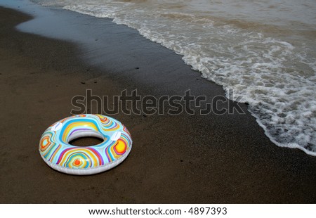 A float ring sitting on the beach as the tide comes in.