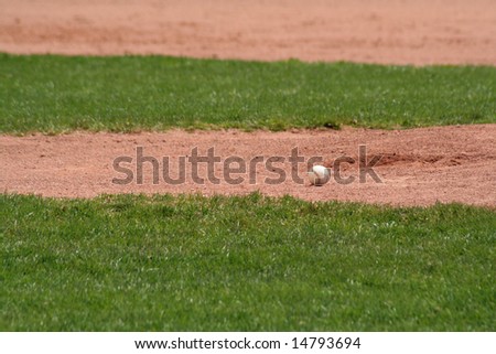 A baseball sitting in front of the pitchers mound.