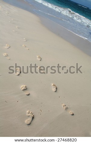 A pair of footprint trails on a tropical beach.