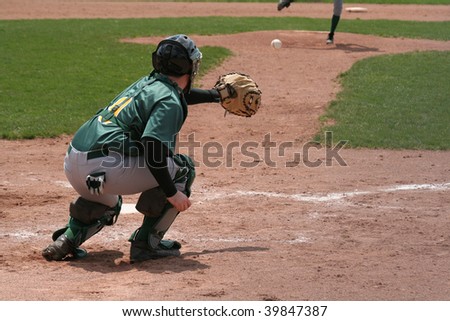 A catcher coming out his crouch to catch the pitch.