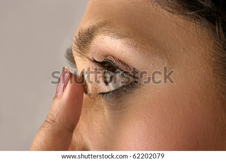 Young woman  inserting a contact lens in her eye,  close-up