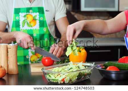 Man and woman in the kitchen. they cook vegetables and salad for dinner or lunch
