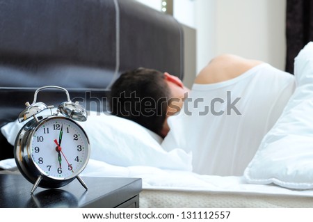 Man sleeping with alarm clock in foreground