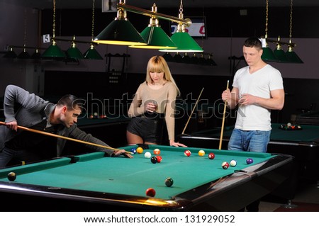 Young attractive people aim at game at billiards