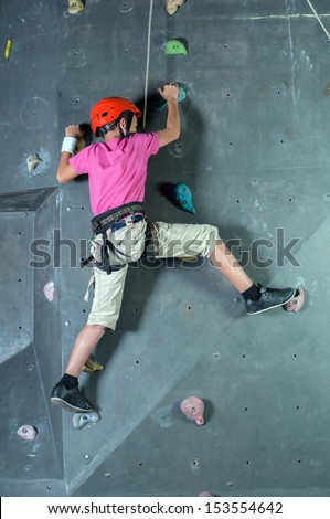 Child climbing on a wall in a climbing center.