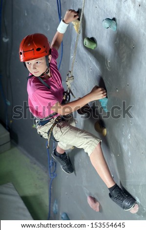 Child climbing on a wall in a climbing center.
