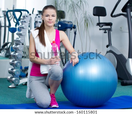 Fitness woman. Portrait of cheerful young attractive woman with bottle of water, at fitness club or gym