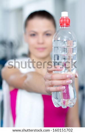 Fitness woman. Portrait of cheerful young attractive woman with bottle of water, at fitness club or gym