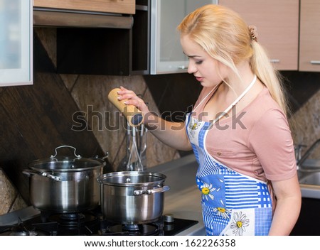 Kitchen Woman. Beautiful happy smiling woman in kitchen interior cooking in pot