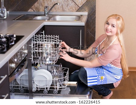 Kitchen Woman. Girl in the kitchen using dishwasher. view of young woman in kitchen doing housework.