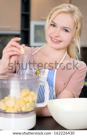 Kitchen Woman. Young woman preparing fruits for the blender