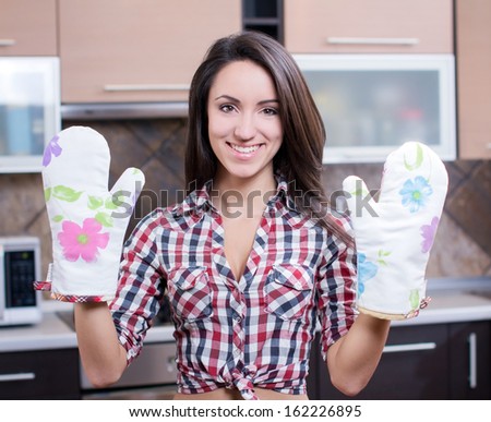 Kitchen Woman. Portrait of cheerful young beautiful woman in mittens  in the kitchen
