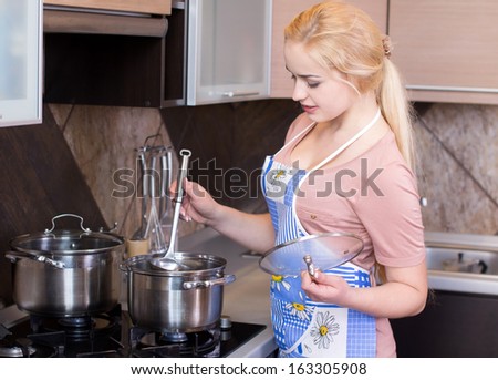 Kitchen Woman. Beautiful happy smiling woman in kitchen interior cooking in pot