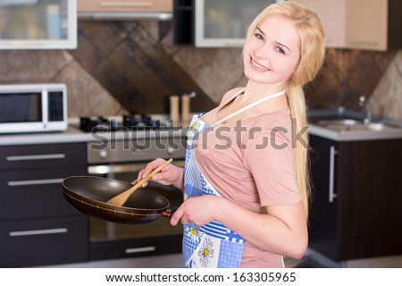 Kitchen Woman. Young beautiful girl holding a frying pan. Cooking. Kitchen background