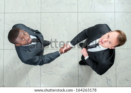 African businessman shaking hands with a caucasian one. view from above