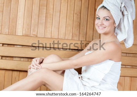Spa & Wellness. Woman sitting on wooden bench, relaxing in sauna at health spa center.