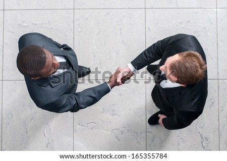 African Businessman Shaking Hands With A Caucasian One. View From Above
