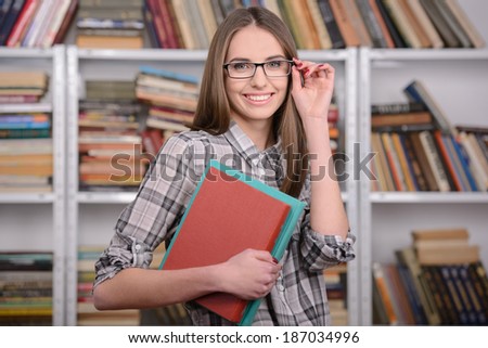 Portrait of a beautiful young student girl reading book in library