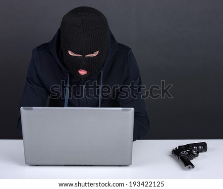 Computer hacking. Angry young men in balaclava gesturing and looking at the computer monitor