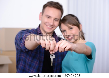 Key of their new house. Happy young couple standing close to each other and smiling while holding key from the house