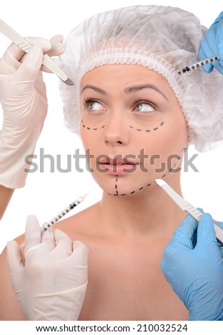 Plastic surgery. Terrified young woman looking away while many hands holding syringes and scalpels near her face