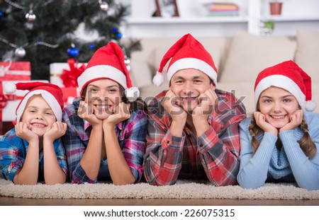 Portrait of friendly family are looking at camera on Christmas evening. Christmas Tree. Santa Hat.