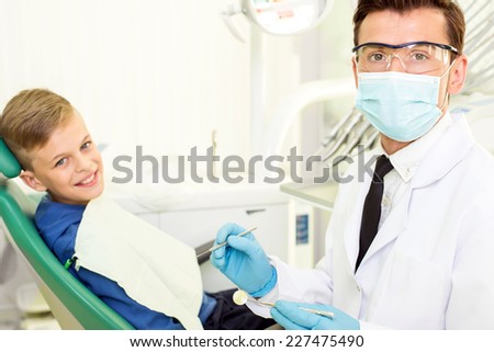 Young doctor and the little boy in the dentist\'s office are looking into the camera.